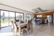 Mesa de comedor de madera con cómodas sillas, cocina moderna y vistas a la terraza y al jardín