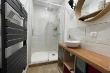 Salle de bain avec douche à l'italienne, vasque élégante et miroir éclairé.